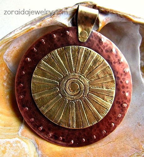 A brass "Sun" on a hammered, textured copper circle